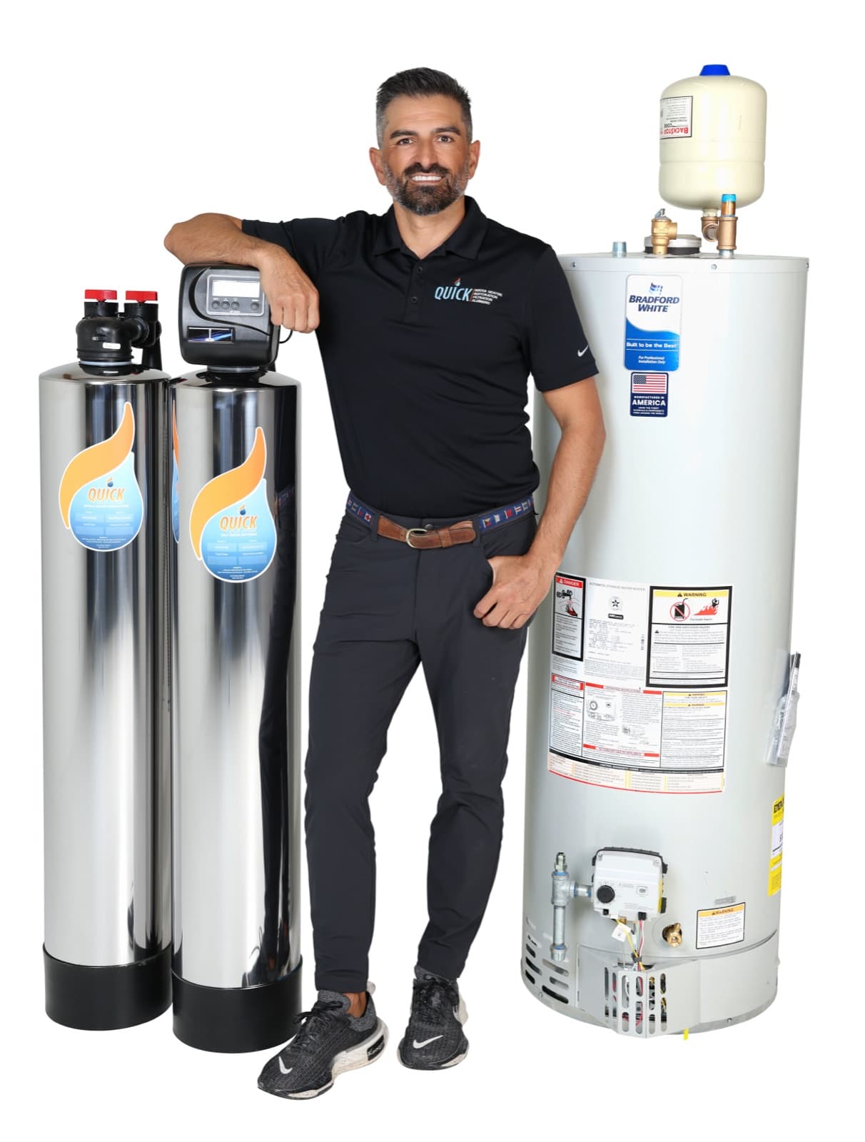 A Quick Water Heater technician leaning on a Bradford White gas water heater, beside two Quick filtration tanks
